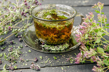 Homemade Oregano, Origanum vulgare herbal tea in a tea cup. Steaming hot drink with dry and fresh...