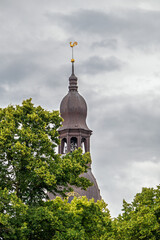 Dome Cathedral tower with a golden rooster on top. View of the tower against a cloudy sky