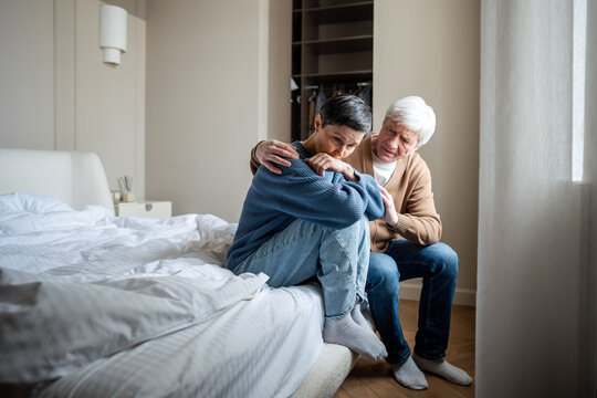 Elderly couple in grief. Mature wife in distress wronged in sorrow, marital disagreement, husband calming embrace and giving water. Conflict resolution, emotional repair, stress relief, reconciliation - Powered by Adobe