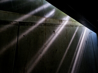 Between the walls and ceiling in the tunnel, rays of light shine through a crack. The slightly...
