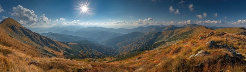 Panoramic mountain vista.  Autumnal peaks and valleys stretch into the distance under a bright sun.  A golden-brown landscape of high, rolling hills, dotted with hardy vegetation, leads to a hazy.