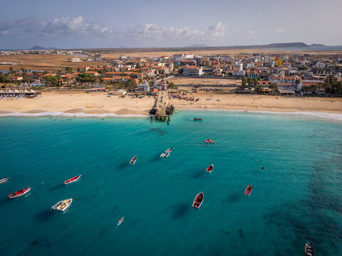 Aerial drone shot of the Santa Maria pier and beach, Sal Island, Cape Verde, at golden sunset. Turquoise waters, fishing boats and a tropical atmosphere in high resolution.