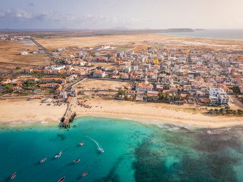 Aerial drone shot of the Santa Maria pier and beach, Sal Island, Cape Verde, at golden sunset. Turquoise waters, fishing boats and a tropical atmosphere in high resolution.