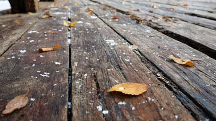 Old wooden deck with dried leaves and snow crystals