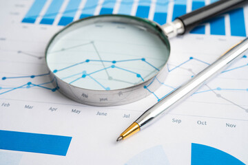 Magnifying glass on data business graphs paper.