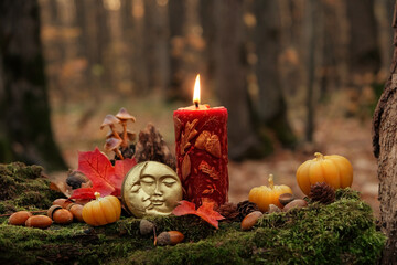 burning magic candle, moon amulet, decorative pumpkins in autumn forest, nature background. mystery...