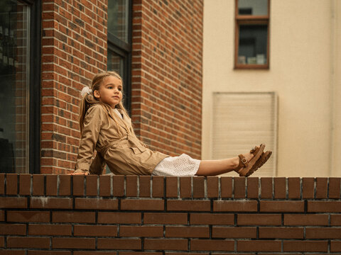 young girl in beige trench coat sitting on the stairs