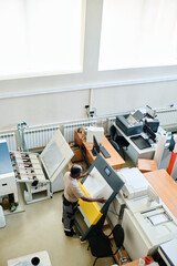 High angle extreme long shot of mature African American man working in modern printing house equipped with new machinery