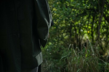 A samurai in black kimono is walking through forest.