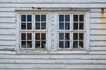 Weathered wooden windows show a textured surface as they reflect the outside environment on a calm...