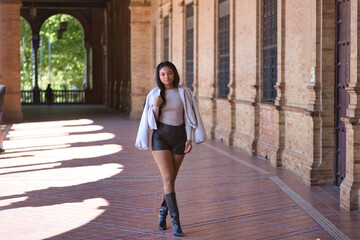 Young, beautiful, African woman, with jacket, leather shorts and boots, posing and modeling in the...