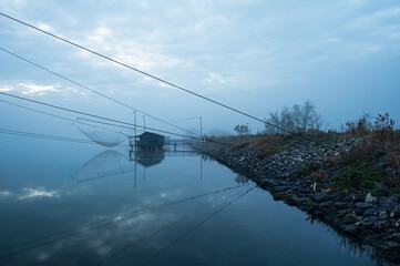 fishing houses inside the Po river Delta lagoon in an autumnal morning, Comacchio, Ferrara, Italy
