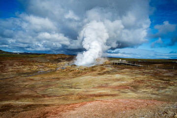 Geothermal area in Iceland. A desert land with orange soil. Thick white steam escapes from cracks...