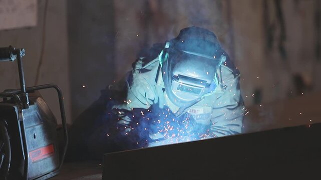 Welders welding large steel sections, structures, steel boxes and trusses. Welders weld large steel sections of a bridge's box girder. Close-up. A shipyard or metal fabrication plant, inside