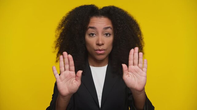 Serious woman making stop gesture on yellow