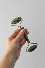Woman’s hand holding jade facial massage roller