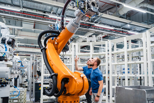 Two technicians examining industrial robot in a factory