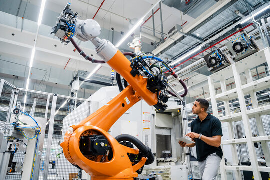 Technician examining industrial robot in a factory