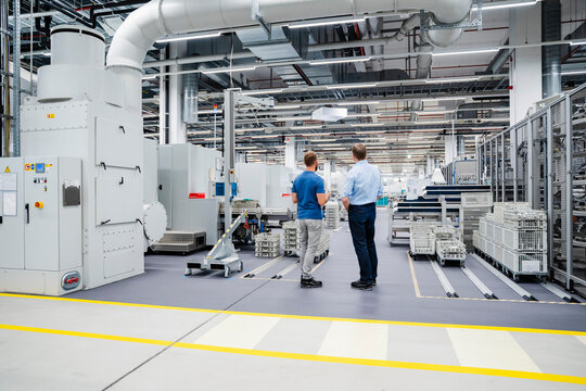 Rear view of businessman and employee standing in a factory