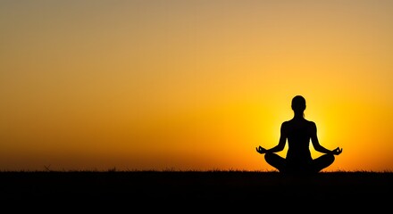 Silhouette of a person meditating in lotus position against a vibrant orange and yellow sunset sky.