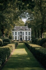 Obraz premium Elegant manor surrounded by lush greenery and neatly trimmed hedges creates a tranquil atmosphere in a serene landscape during midday