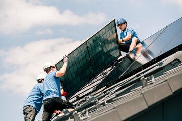 Engineers wearing hardhats and installing solar panels on rooftop