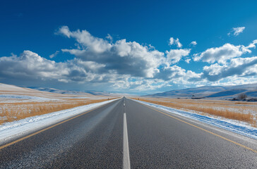 Empty asphalt road and blue sky with clouds in the background, a panoramic view of a highway for car or vehicle travel in the winter season.