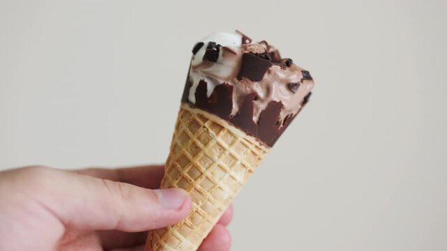 Close-up of a man holding a chocolate cornetto ice cream