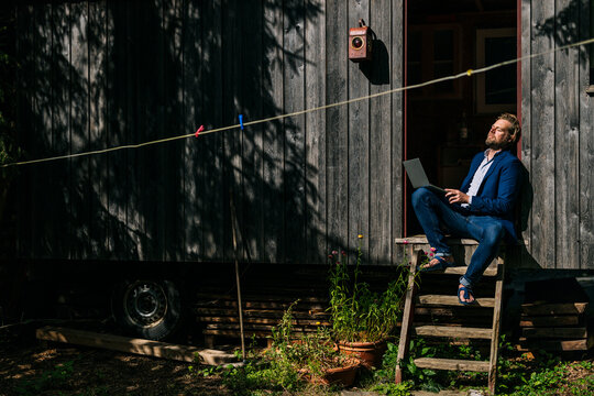 Businessman resting and sitting at doorway of log cabin