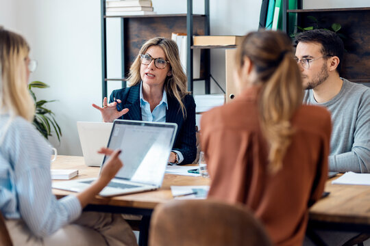 Businesswoman wearing eyeglasses discussing with colleagues in office