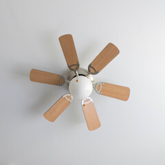 Ceiling fan with light wooden blades and a central light bulb, set against a pristine white ceiling, perfect for interior design, home decor, or architectural stock collections