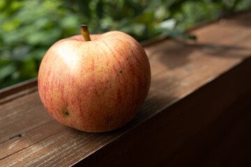 Ripe red apple on a wooden terrace in the garden. Still life with red apple.