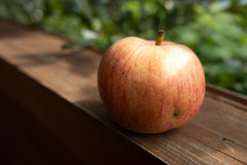 Ripe red apple on a wooden terrace in the garden. Still life with red apple.