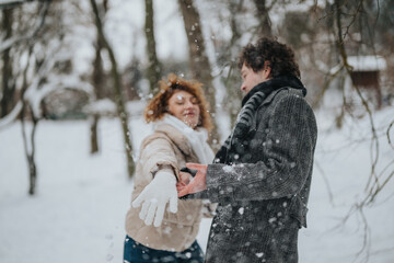 A joyful scene of a couple playfully engaging in a snowball fight during a snowy day. The happiness...