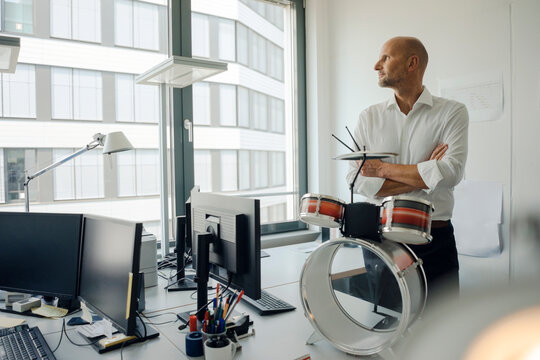 Businessman standing in his office, plaing drums