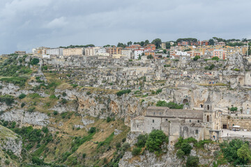 Matera – Panoramic View of Sassi District with Chiesa di San Pietro Caveoso on Rocky Cliff,...