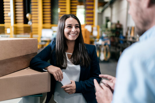 Young woman working in distribution warehouse, talking to colleague - Powered by Adobe