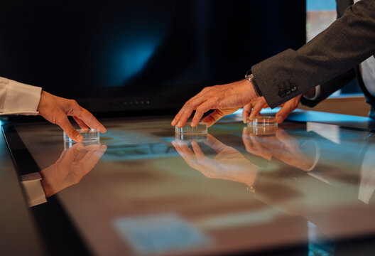 Hands collaborating on futuristic touchscreen technology in modern office