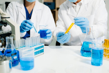 scientists in lab coats conducting research, handling glassware, and working with chemicals in a...