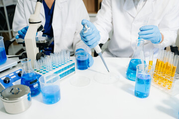 scientists in lab coats conducting research, handling glassware, and working with chemicals in a...