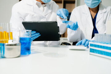 Scientists in a clean lab environment analyzing samples using test tubes and a tablet, showcasing...