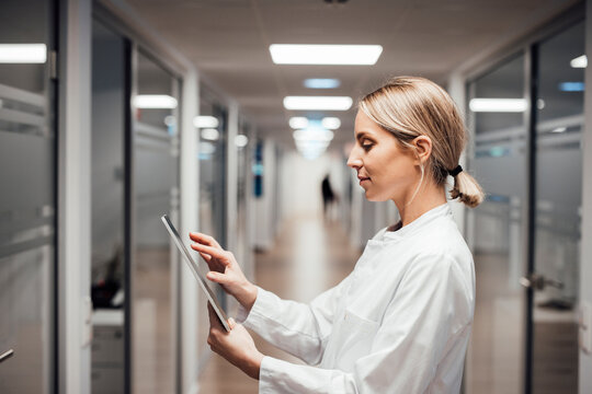 Doctor analyzing CT images on tablet in modern clinical corridor