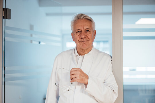 Doctor in white lab coat standing in modern clinic looking at camera