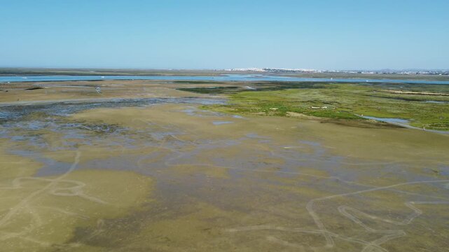 Ria Formosa with riverbed exposed at low tide and Faro in the background on Algarve in Portugal