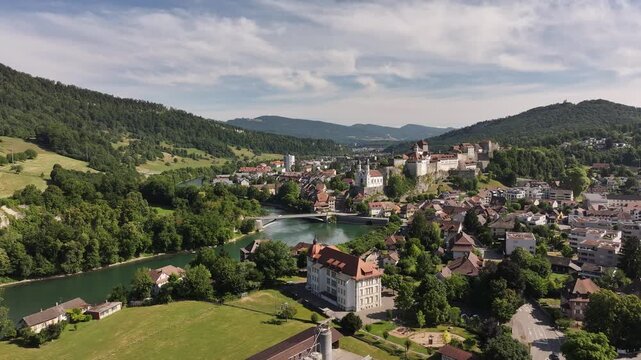 Scenic aerial view of Aarburg Castle, charming old town and Aare river in Canton Solothurn, Switzerland, surrounded by lush green hills under summer sky.
