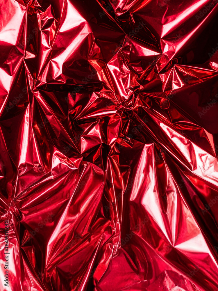 Poster a rich and textured close-up of deeply crumpled red foil, showcasing its glossy surface with dramati