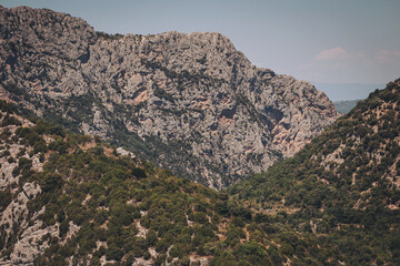 Obraz premium Majestic rock formations rise above lush valleys under a clear sky in a tranquil mountain landscape at midday