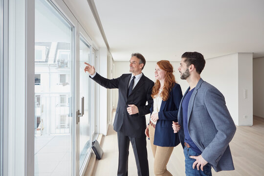 Businessman pointing at view to young couple from new apartment