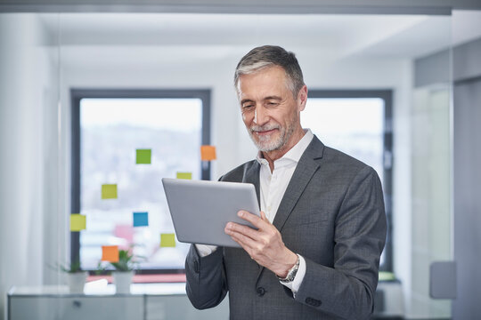 Smiling senior businessman working on tablet PC in office