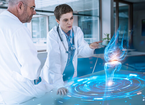 Doctors analyzing holographic knee anatomy in medical consultation